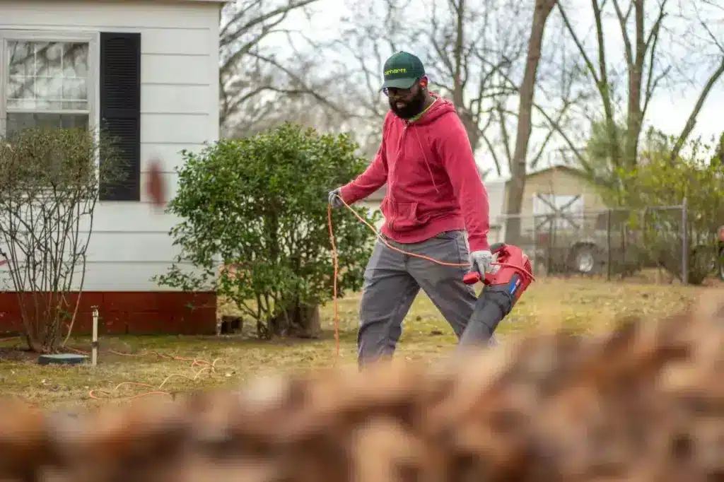 A man in a red jacket operates a leaf blower