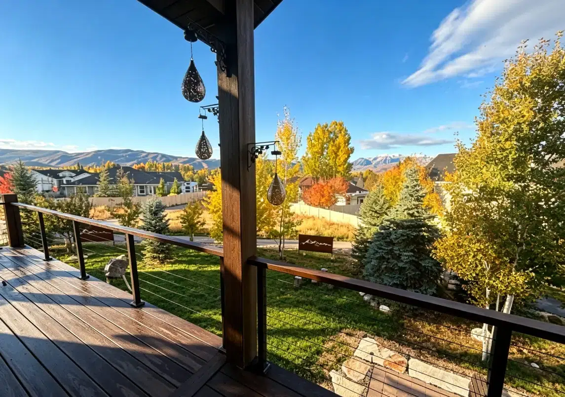Wooden deck overlooking colorful autumn landscape with mountains in the distance under clear blue sky