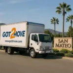 Moving truck parked beside San Mateo sign under clear blue sky with palm trees in background