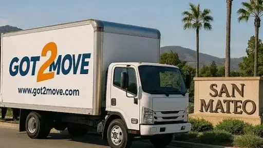 Moving truck parked beside San Mateo sign under clear blue sky with palm trees in background
