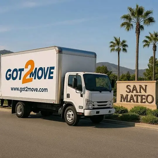 Moving truck parked beside San Mateo sign under clear blue sky with palm trees in background
