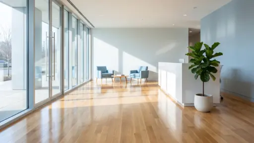 Spacious office lobby with blue armchairs, large windows, and a potted plant on wooden floor