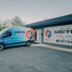Blue heating and cooling service van parked outside a commercial building with signage