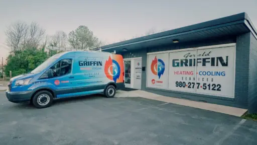 Blue heating and cooling service van parked outside a commercial building with signage