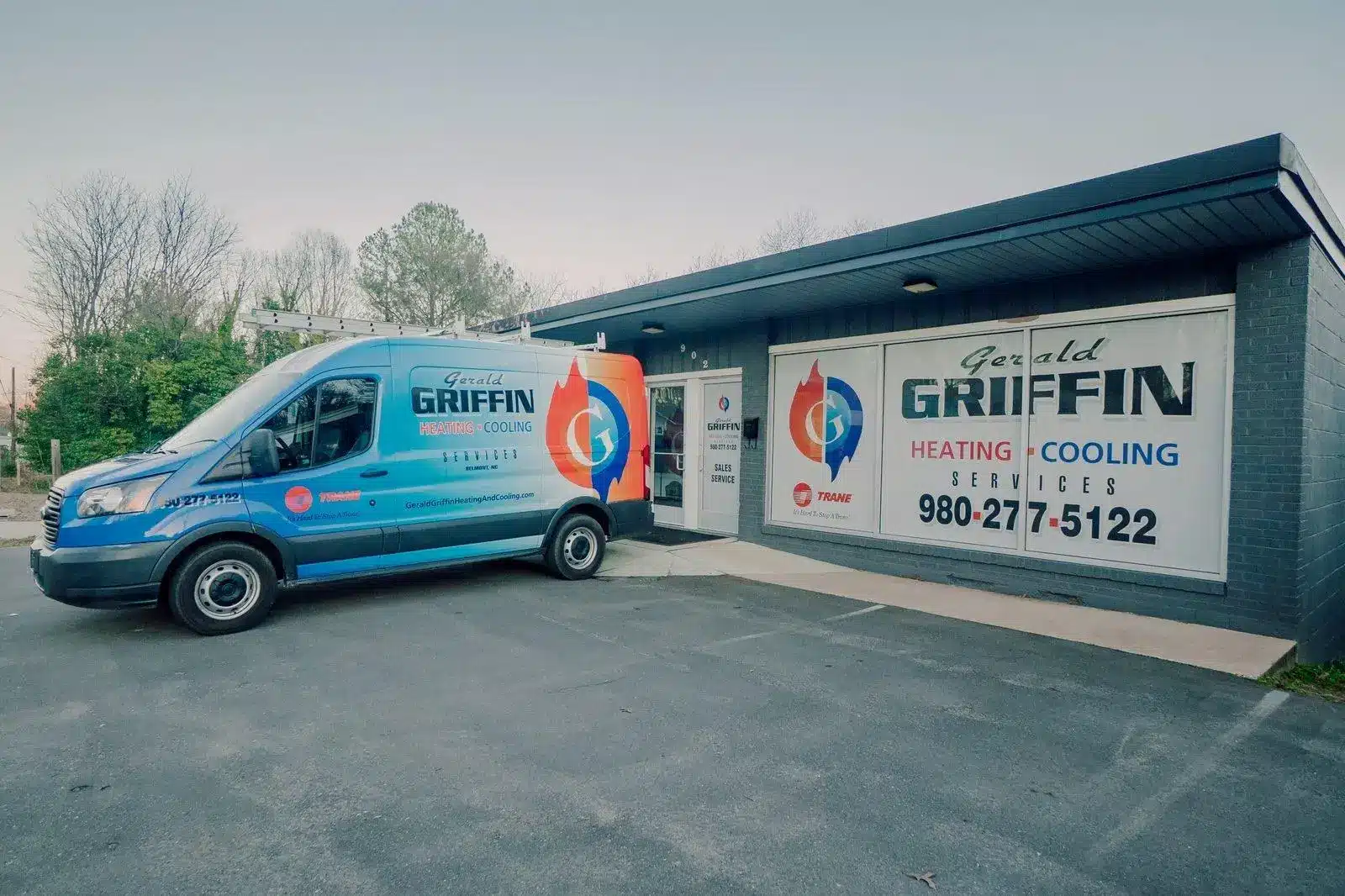 Blue heating and cooling service van parked outside a commercial building with signage