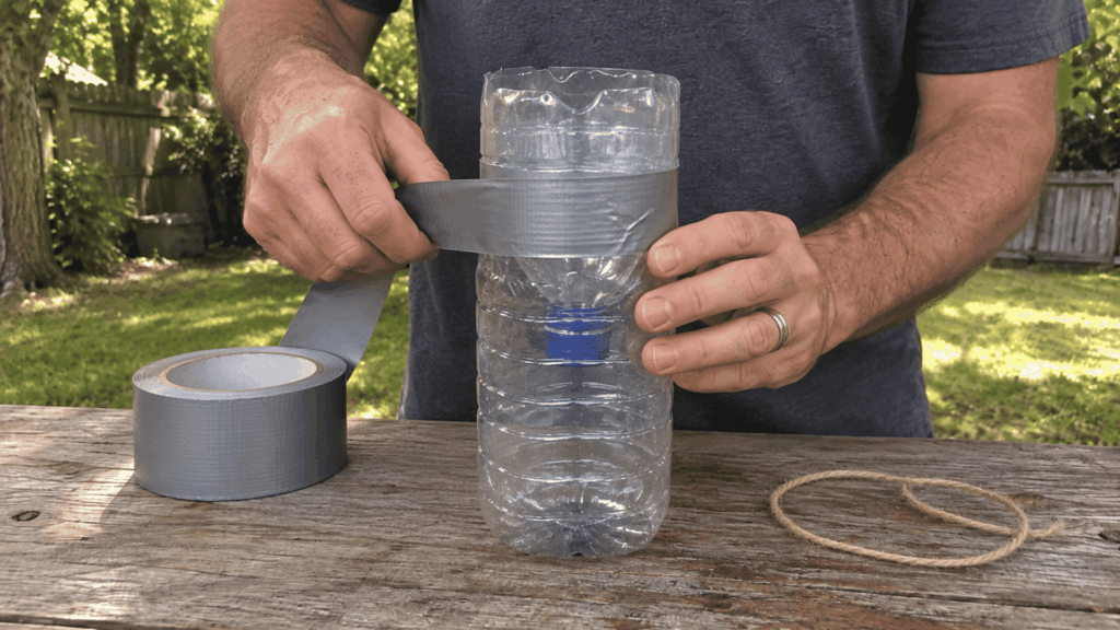 securing the inverted bottle funnel with duct tape while making a homemade wasp trap