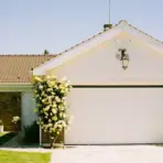 White garage with yellow flowering vines under clear blue sky