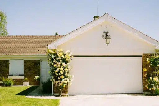 White garage with yellow flowering vines under clear blue sky
