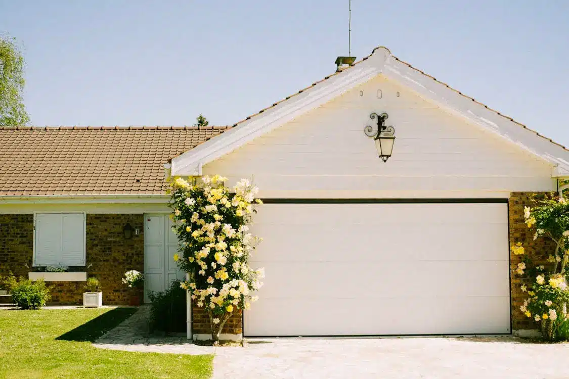 White garage with yellow flowering vines under clear blue sky