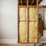exposed wall framing shows vertical wooden studs behind drywall with insulation and wiring visible