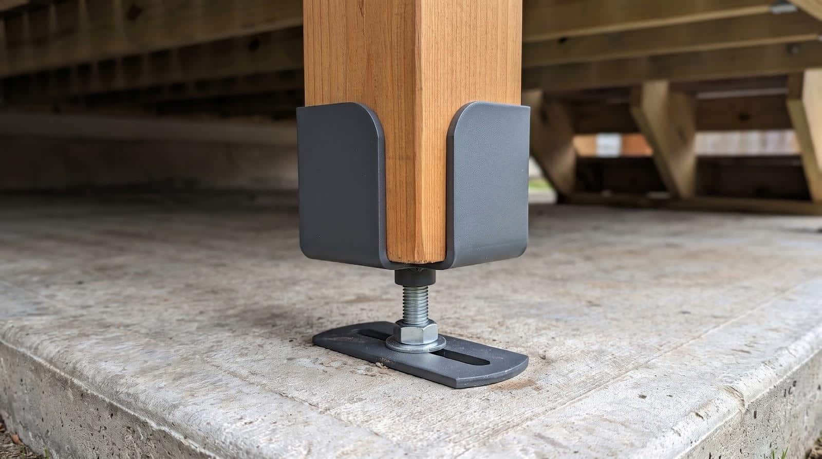Wooden post secured with metal bracket on concrete foundation under a deck structure