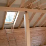 Wooden loft interior with exposed beams and skylight under natural daylight