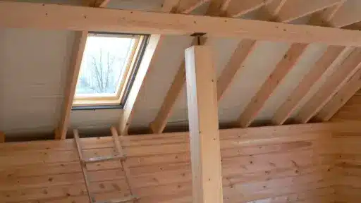 Wooden loft interior with exposed beams and skylight under natural daylight
