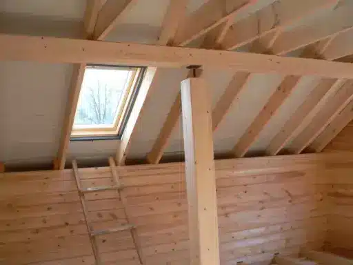 Wooden loft interior with exposed beams and skylight under natural daylight