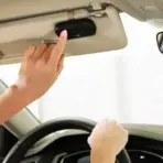 Person pressing button on car's overhead console while driving