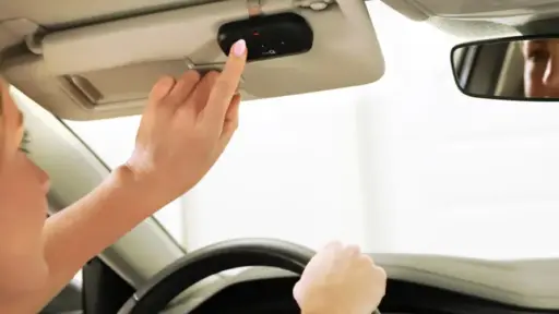 Person pressing button on car's overhead console while driving