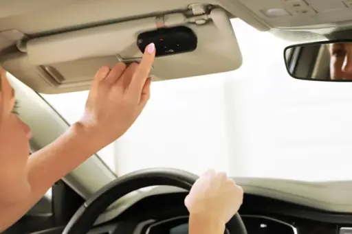 Person pressing button on car's overhead console while driving