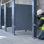Construction worker installing restroom partitions in an unfinished building site