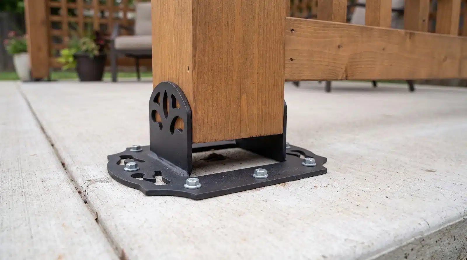 Wooden post secured with metal bracket on concrete patio with outdoor furniture in background
