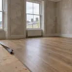 Newly installed hardwood floor in partially renovated room with large windows and view of rooftops