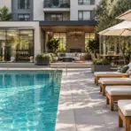 Poolside lounge chairs under umbrellas near modern gym with glass facade