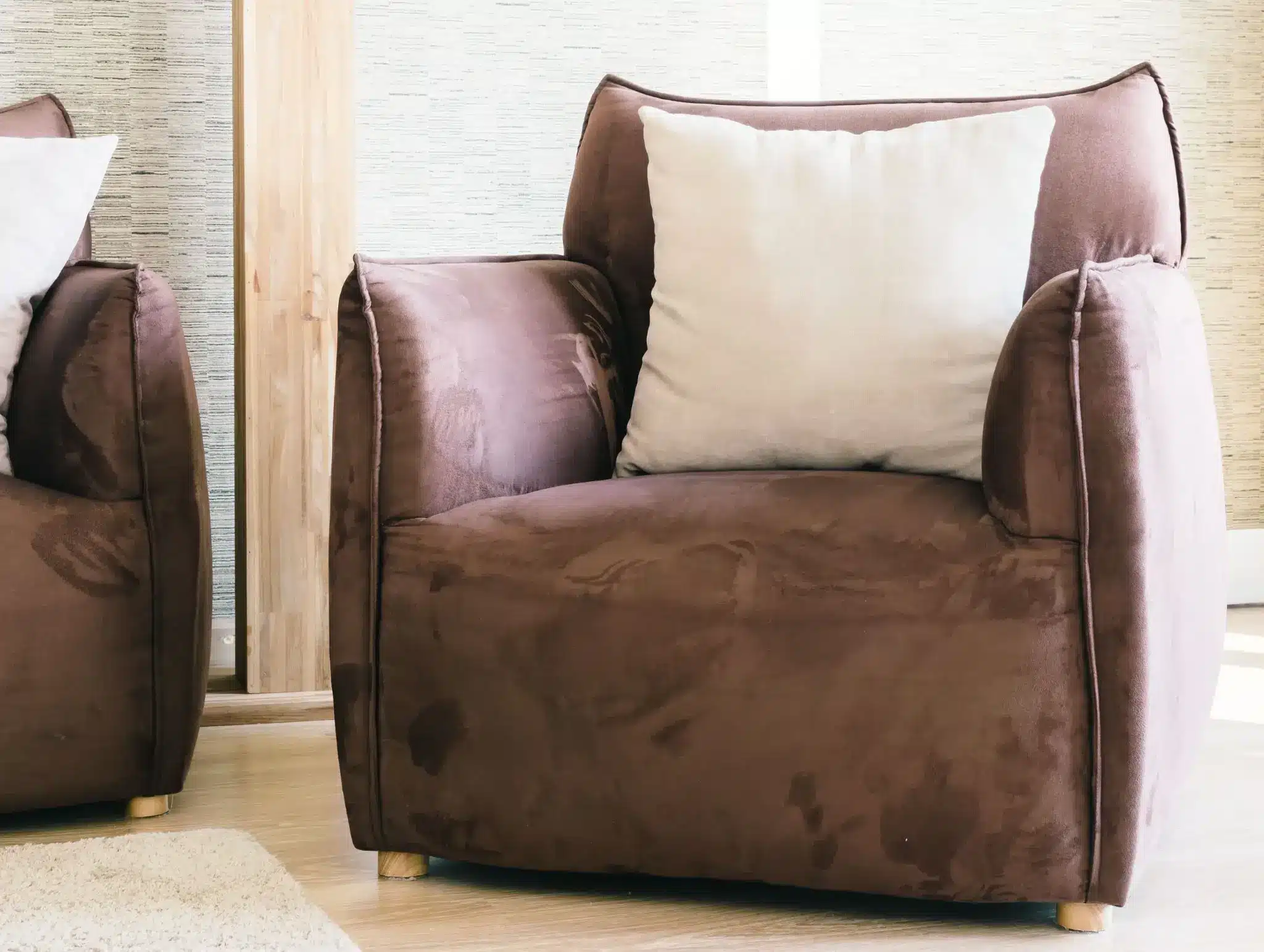 Brown suede armchairs with white cushions in bright living room setting